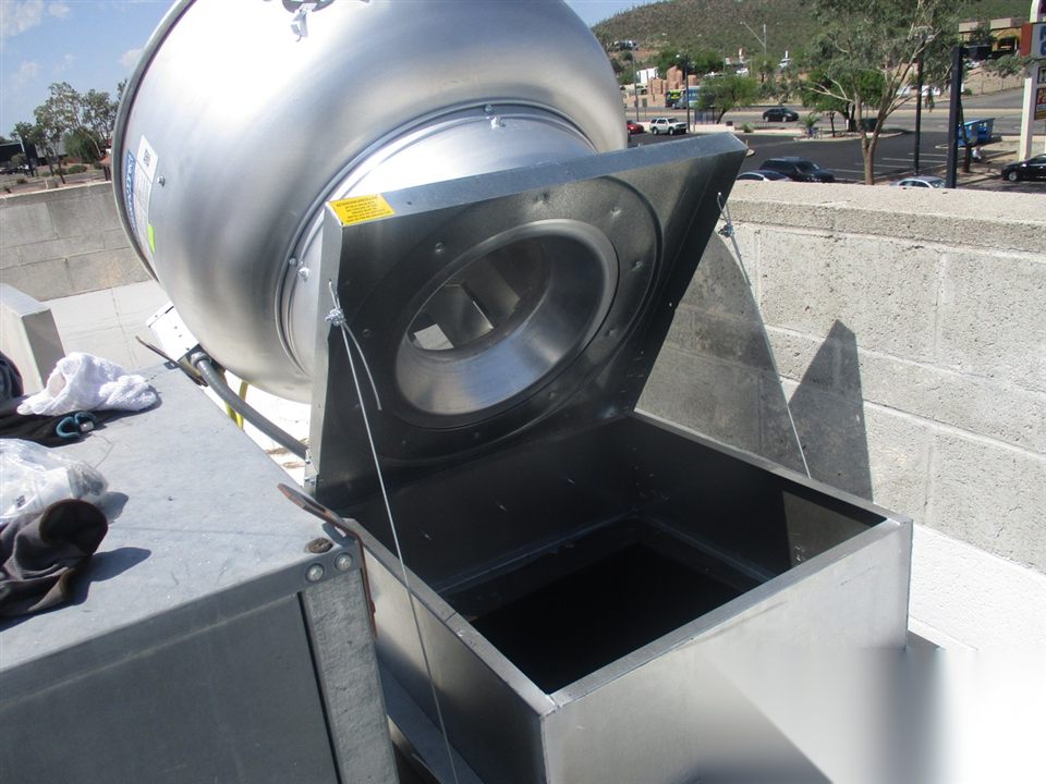 Rooftop upblast exhaust fan opened on hinges for cleaning and maintenance access